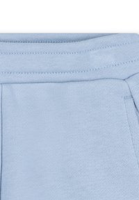 Pantalons de jogging en coton bleu clair avec une texture lisse, une taille élastique et des détails cousus sur les coutures et les poches.