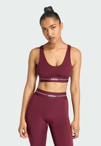 Burgundy sports bra and matching leggings, made of stretch fabric, featuring white logo bands and a fitted design for comfort and support.