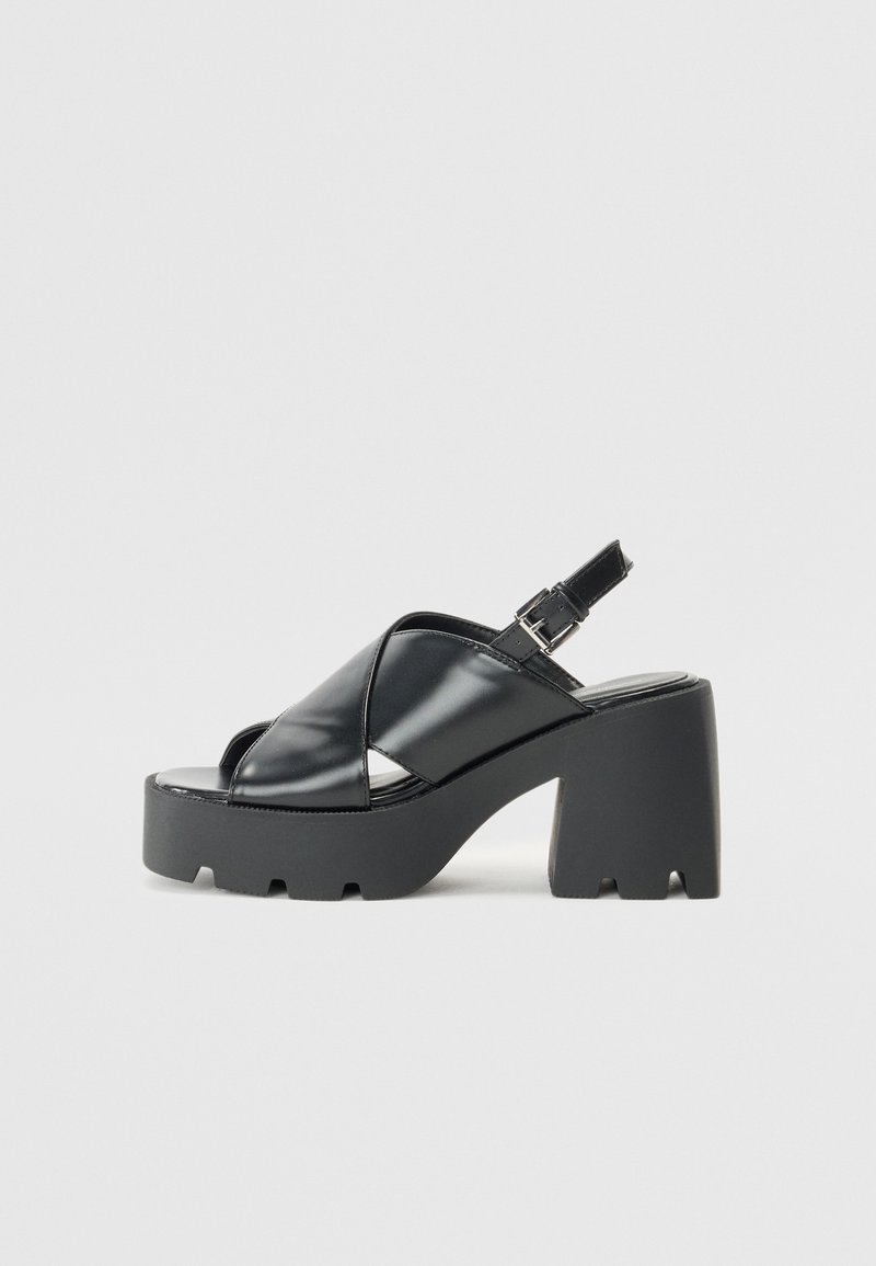 Sorte, patentlær slingback plattformsandaler med en chunky hæl, med design av tverrremmer og en teksturert såle for grep.