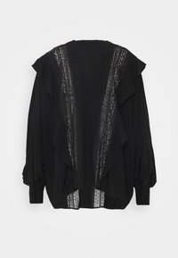 Blusa nera con strati arricciati, pois testurizzati e un bordo in pizzo al centro. Maniche lunghe con polsini con bottoni.