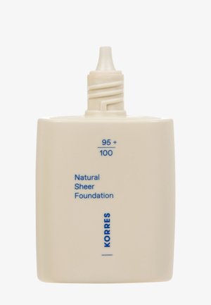 Korres Natural Sheer Foundation in a square, cream-colored container with a twist applicator. Text on the front is blue.