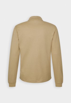 Polo a maniche lunghe color beige, realizzata in misto cotone. Presenta un colletto e polsini a coste. Texture liscia senza motivi o disegni visibili.