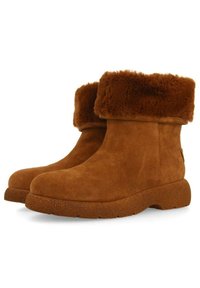 Botas de ante marrón hasta el tobillo con un suave y esponjoso puño de pelaje, puntera redondeada y suela de goma texturizada. Diseño simple sin hardware visible ni patrones.