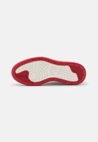 Semelle de chaussure avec une bande de roulement en caoutchouc rouge et blanc comportant des motifs circulaires et linéaires pour l'adhérence et la flexibilité.