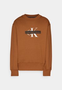 Sudadera marrón con cuello redondo, puños y cintura acanalados. Presenta un logo blanco "ck" y el texto "Calvin Klein Jeans" en el centro.