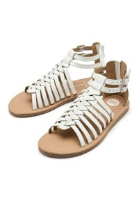 Sandali bianchi in pelle con cinghie intrecciate, fibbie alla caviglia e suola in gomma marrone, caratterizzati da una punta arrotondata e una soletta texturizzata.
