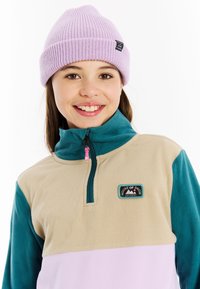 Fleece pullover in beige, teal en lichtroze, met een half-rits kraag en een ronde patch met het label "HOUSE OF SNOW." Gebreide lavendel beanie.