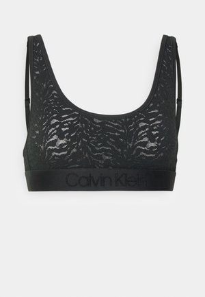 Bralette en dentelle noire avec un motif floral, un décolleté en scoop, des bretelles fines et une bande solide avec "Calvin Klein" embossé en noir.