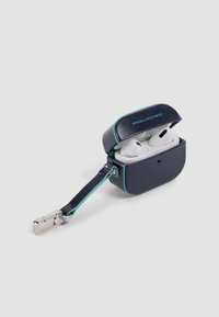 Estuche de cuero azul marino con detalles en azul claro; contiene auriculares inalámbricos blancos. Incluye un accesorio metálico en una correa.