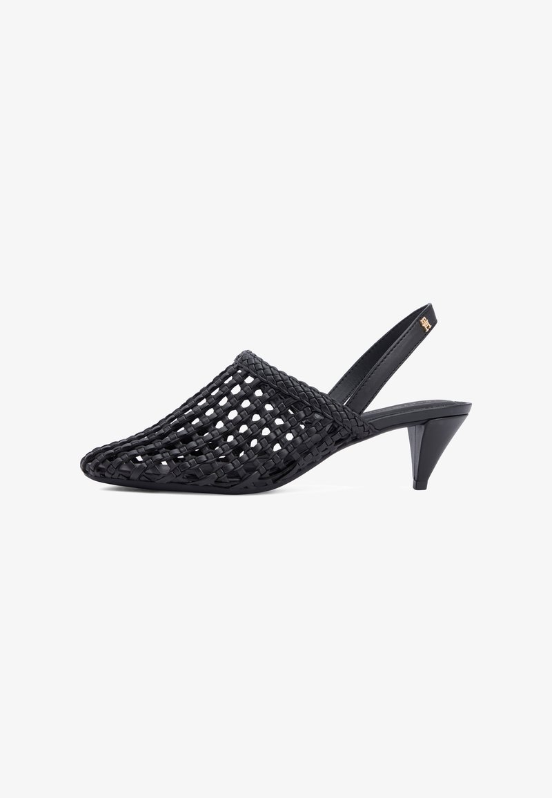 Mule negro con tira trasera, diseño de celosía abierta tejida y tacón bajo cónico, con un pequeño emblema dorado en la correa.