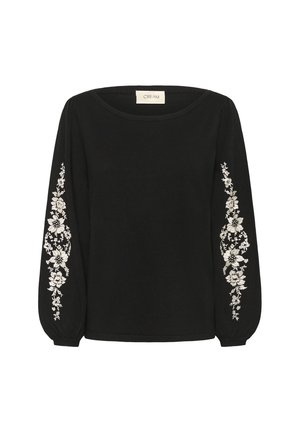 Blouse noire à manches longues avec un col rond et des broderies florales blanches courant verticalement le long des deux manches. Poignets élastiques sur les manches.