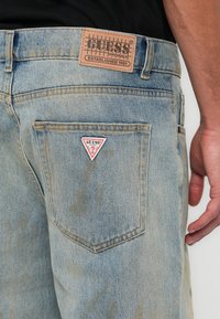 Lichte blauwe denim jeans met een gedragen textuur. Kenmerkt zich door een leren label en een merk driehoek logo op de achterzak. Slanke pasvorm.
