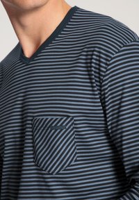 Blauw en zwart gestreefd langarmshirt met een V-hals en een borstzak. De stof lijkt zacht met een gladde textuur.