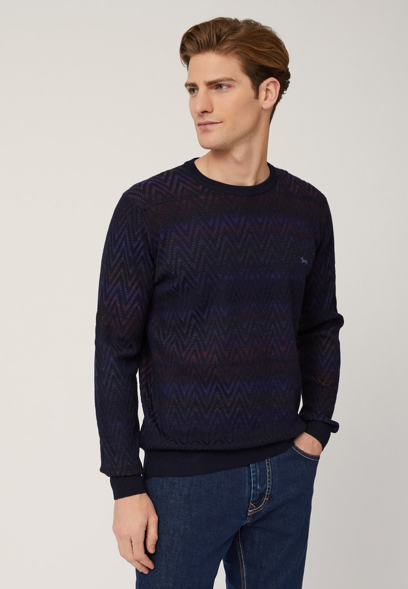 Maglione blu navy con motivo a zigzag, texture a maglia e scollatura a girocollo. Presenta maniche lunghe e polsi e orlo a costine.
