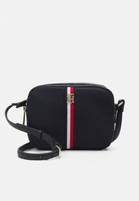 Schwarze Nylon-Crossbody-Tasche mit goldenen Beschlägen, ausgestattet mit einem zentralen rot-weißen Streifen, Reißverschluss und verstellbarem Tragegurt.