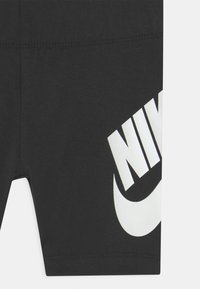 Pantaloni corti neri Nike realizzati in tessuto morbido, con un grande logo bianco e una superficie liscia. Vestibilità aderente con una cintura elastica.