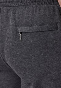 Donkergrijze sweatpants met een gladde structuur, een elastische tailleband en een klein ritszakje aan de achterkant met een metalen trekhaak.