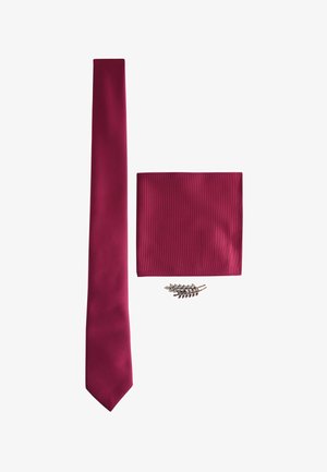 Burgunderroter Seidenschal, passendes Einstecktuch und eine silberne, blattförmige Reversnadel. Alle Artikel zeichnen sich durch glatte Texturen und satte Farben aus.