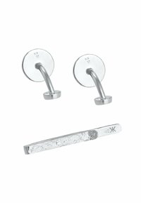 Ganci da parete in argento presentano un design liscio e arrotondato con una base circolare. Una barra metallica piatta e texturizzata è posizionata sotto.