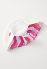 Bonnet de bain blanc avec des rayures ondulées roses, rouges et violettes, partiellement plié et posé sur une surface blanche.