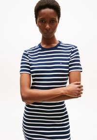 Navy and white striped t-shirt dress, short sleeves, crew neck, ribbed texture, featuring a small logo on the left chest.