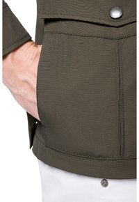 Oliwkowa kurtka o gładkiej fakturze, z przednią kieszenią, akcentem w postaci zatrzasku oraz zbliżeniowym widokiem na rękaw i obszar kieszeni.