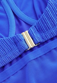 Maillot de bain bleu avec tissu texturé plissé, une fermeture en métal doré et une doublure lisse. Il dispose de bretelles réglables et d'une sous-couche en mesh.