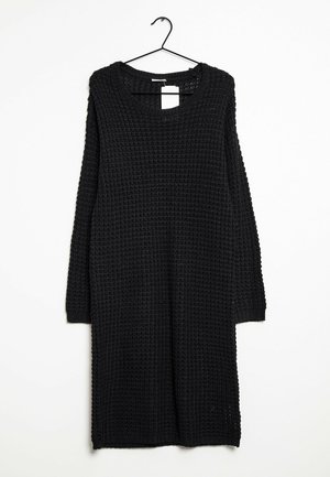 Musta pitkähihaine neulemekko, jossa on teksturoitu kuviopinta ja pyöreä pääntie. Mekossa on myös sivureiät ja resorit hihansuissa.