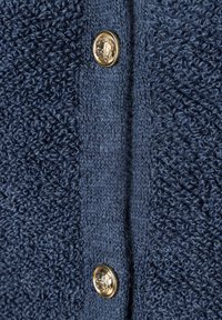 Navyblauer, strukturierter Cardigan mit weichem, flauschigem Strick und glatten Strickarten an den Seiten. Goldfarbene dekorative Knöpfe mit einer prägenden Detail.