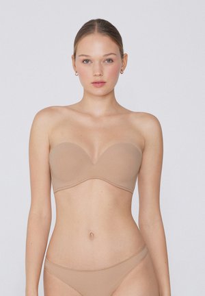 Soutien-gorge bandeau beige avec bonnets lisses et moulés, et fines armatures. Tissu doux, design sans coutures et style minimaliste.
