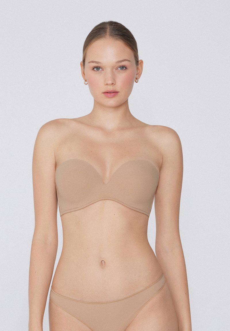 Béžová bezramínková podprsenka s hladkými, tvarovanými košíčky a tenkým drátem. Měkká látka, bezšvový design a minimalistický styl.