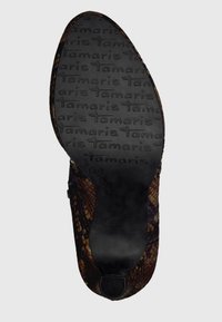 Czarna gumowa podeszwa z teksturowanym logo Tamaris. Wierzch pokryty brązowym wzorem wężowej skóry. Okrągły kształt z gładkim wykończeniem.