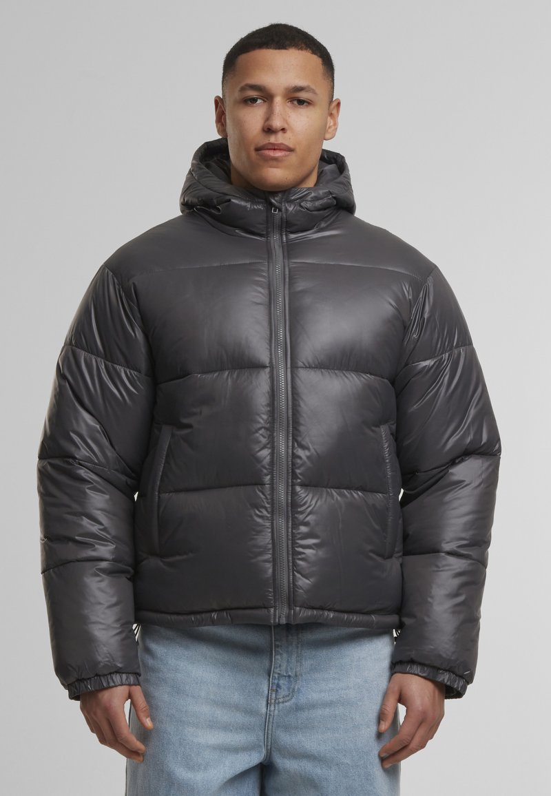 Tamsiai pilkas pūkų džemperis, su užtrauktuku priekyje, kapišonu ir megztomis rankogaliais. Medžiaga atrodo blizgi, su laikytomis kvadratėmis.