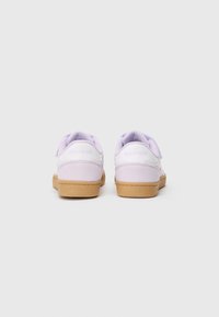 Baskets violettes avec une tige lisse, des accents blancs et une semelle en gomme texturée. Dotées d'une sangle Velcro et d'un col rembourré pour le confort.
