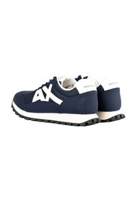 Baskets Armani Exchange bleu marine et blanc avec logo « AX » sur le côté, languette blanche au talon et semelle en caoutchouc noire vues de l'arrière en angle latéral.