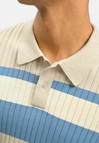 Ljusbeige polo-shirt med vertikal ribbning och horisontella blå ränder. Den har en krage och en enkel knappslå.