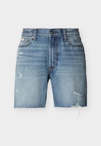 Κοντό τζιν παντελόνι σε ανοιχτό μπλε χρώμα με ξεφτισμένα τελειώματα, φθαρμένες λεπτομέρειες και στα δύο πόδια, κλείσιμο με κουμπιά μπροστά και μπροστινές τσέπες, πάνω σε λευκό φόντο.