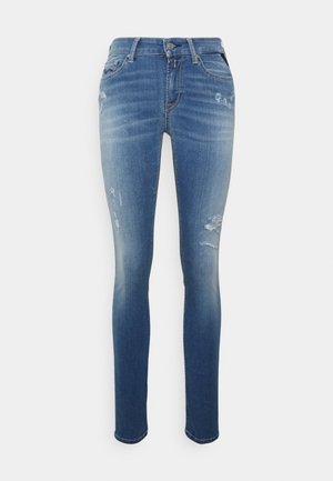 Jeans ajustados de color azul, hechos de denim, con un acabado desgastado, áreas desgastadas, diseño de cinco bolsillos y cierre de botón.