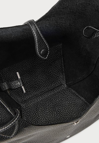 Interior de uma bolsa de couro preto com material texturizado, fecho de bolso visível e detalhes de costura. O revestimento é macio e de cor escura.