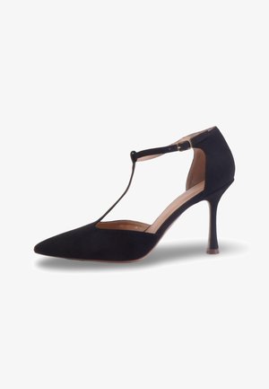 Chaussure à talon haut noire à bout pointu avec bride en T et boucle à la cheville, finition en daim, talon fin de hauteur moyenne, doublure intérieure beige.