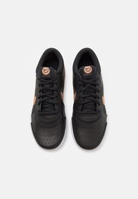 Scarpe sportive nere con tomaia in pelle perforata, accenti in pesca a contrasto, punta tonda, lacci piatti e suola in gomma. Logo sulla linguetta.