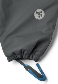 Grijze waterdichte jas met elastische manchetten, blauwe verstelbare trekker en een ronde logo met het woord "WHEAT" in een vetgedrukt lettertype.