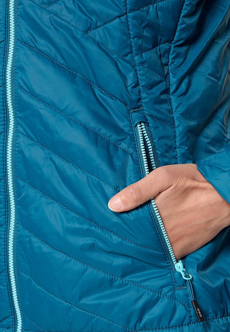Giacca isolante teal con texture trapuntata, dotata di tasca laterale con zip e zip di un contrastante azzurro chiaro, finitura dal leggero sheen.