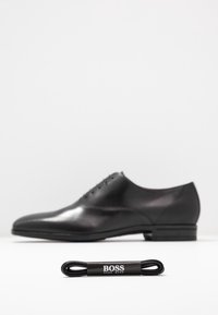 Chaussure habillée en cuir noir avec une finition polie, dotée d'un bout rond et d'un design à lacets, accompagnée de lacets noirs arborant la marque "BOSS".