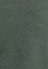 Tessuto a maglia rigata di un colore verde tenue, con una superficie texture e linee verticali. Nessun accento o motivo notevole visibile.