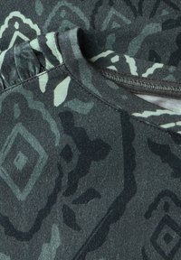Šedá vzorovaná látka se strukturálním povrchem a jemným motivem v tmavě zelených odstínech a světlými akcenty, s kulatým výstřihem a nabíraným detailem.
