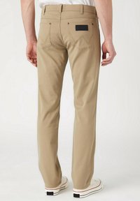 Beige katoenen broeken met een recht gesneden ontwerp, voorzien van twee achterzakken met een zigzagsteek en een zwart label op de tailleband.