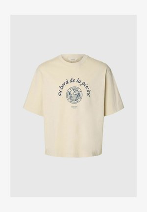 Krém színű rövid ujjú póló kerek nyakkivágással, tengerészkék francia szöveggel és egy kör alakú hal grafikával egy medencében.