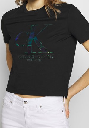 Czarny krótki t-shirt z odbijającym logotypem "CK" i napisem "CALVIN KLEIN JEANS NEW YORK". Krótkie rękawy i gładki materiał bawełniany.