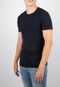 Navyblauwe t-shirt gemaakt van zachte katoen, met een ronde hals, korte mouwen en een slim-fit ontwerp. G gedragen met lichtblauwe jeans.
